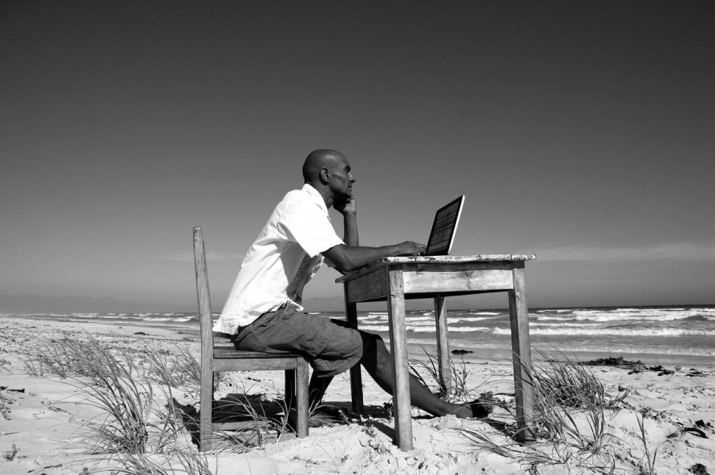 Bald man working at his desk on the beach, accountant